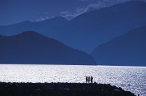 Silhouettes of people on shore overlooking Coastal Mountains, Howe Sound, British Columbia, Canada — Stock Photo