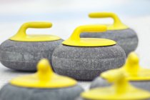 Close-up of yellow curling stones on ice. — Stock Photo