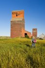 Uomo che esplora vecchi edifici di grano nella città fantasma di Neidpath, Saskatchewan, Canada — Foto stock