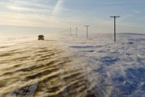 Carro andando na estrada coberta com neve soprando perto de Verwood, Saskatchewan, Canadá — Fotografia de Stock