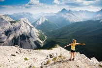 A young woman stands at the summit of the Sulphur Skyline Trail with a view of the Rocky Mountains. Miette Hotsprings, Jasper National Park, Alberta, Canada. — Stock Photo