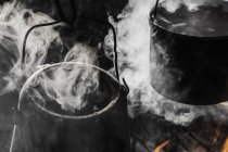 Close-up of campfire with steaming cooking pots — Stock Photo