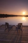 Cadeiras Adirondack no cais de madeira ao nascer do sol no lago Sparrow, Muskoka, Ontário — Fotografia de Stock
