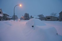 Rue et véhicules couverts de neige au crépuscule dans la ville de ski Revelstoke, Canada — Photo de stock