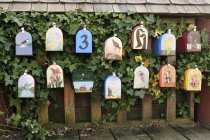 Boîtes aux lettres peintes sur une clôture recouverte de feuillage, Granville Island, Vancouver, Colombie-Britannique, Canada — Photo de stock