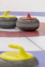 Close-up de vermelho e amarelo curling pedras no gelo . — Fotografia de Stock