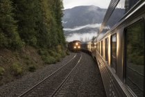Passenger train meeting freight train in mountains. — Stock Photo