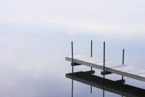 Doca de madeira ao longo da água do rio com reflexão . — Fotografia de Stock