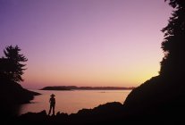 Silueta de persona disfrutando del atardecer en Mackenzie Beach, Vancouver Island, Columbia Británica, Canadá . - foto de stock