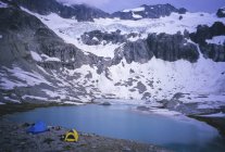Alpine camp with tents and belongings below Mount Redoubt in Cascade Mountains, Washington State, USA — Stock Photo