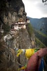 Bandeiras de oração e Taktsang Tigers Nest Mosteiro em rochas acima Paro, Butão — Fotografia de Stock