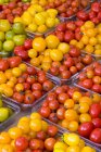 Fresh colorful tomatoes in containers on display at market, full frame. — Stock Photo