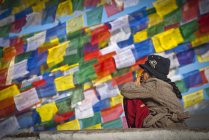 Local mature woman sitting at prayer flags of Boudhanath stupa in Kathmandu, Nepal. — Stock Photo