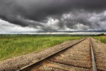 Railroad tracks with storm clouds in country near Didsbury, Alberta, Canada — Stock Photo
