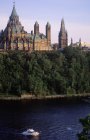 Library of Parliament buildings across Ottawa River with passing boat, Ottawa, Ontario, Canada. — Stock Photo
