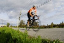 Una persona irreconocible en bicicleta por carretera en Finn Slough, Richmond, Columbia Británica, Canadá - foto de stock