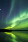 Aurora boreal sobre el lago en el bosque boreal, alrededores de Yellowknife, Territorios del Noroeste, Canadá - foto de stock