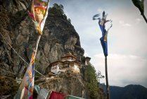 Banderas de oración y Taktsang Tigers Nest Monasterio en rocas sobre Paro, Bután - foto de stock