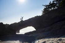 Two hikers standing on top of sea arch at Tsusiat Point, West Coast Trail, Pacific Rim National Park Reserve, Vancouver Island, Canada. — Stock Photo