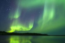 Luzes setentrionais etéreas sobre lago na floresta boreal, arredores de Yellowknife, Territórios do Noroeste, Canadá — Fotografia de Stock