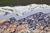 Quarzit-Felsbrocken mit Flechten vor Bergen, die sich im Seewasser spiegeln, Jaspis-Nationalpark, Alberta, Kanada. — Stockfoto
