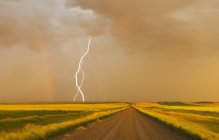 Electrical storm over gravel road in farmland near Val Marie, Saskatchewan, Canada — Stock Photo