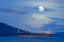 Frachtschiff bei Vollmond im Satellitenkanal in der Nähe der Insel Vancouver, britische Kolumbia, Kanada. — Stockfoto