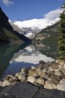 Reflejo de agua de montañas y bosques en Lake Louise, Banff National Park, Alberta, Canadá - foto de stock