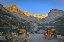 Wooden benches at Lake Ohara with mountains in sunlight in Yoho National Park, British Columbia, Canada. — Stock Photo