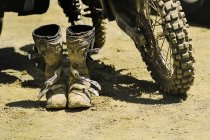 Botas de motocross sucias y rueda trasera de motocross - foto de stock