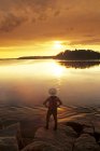 Rear view of man watching sunrise along Numau Lake, Whiteshell Provincial Park, Manitoba, Canada. — Stock Photo