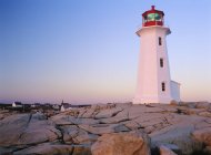 Peggy Cove lighthouse at sunset with village in Nova Scotia, Canada — Stock Photo