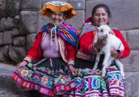 Mulheres locais em roupas tradicionais com cordeiro na rua da aldeia Pisac, Peru — Fotografia de Stock