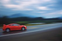 Tiro borrado de carro esporte vermelho na estrada, Colúmbia Britânica, Canadá . — Fotografia de Stock