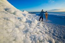 A man with snowshoes looks out over washed up ice piles, along Lake Winnipeg, Manitoba, Canada — Stock Photo