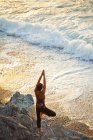Vista de ángulo alto de la mujer haciendo yoga al atardecer cerca de la playa en Kalymnos, Grecia - foto de stock