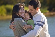 Asian mom and Caucasian dad playing with daughter at Green Lake, Whistler, Canada. — Stock Photo