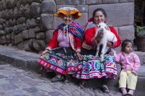 Local women in traditional clothing with child and lamb on street of village Pisac, Peru — Stock Photo