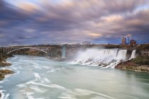 Amerikanische Wasserfälle und Regenbogenbrücke über den Niagara-Fluss, Niagarafälle, New York, USA — Stockfoto