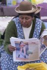 Donna locale che legge il giornale sulla scena del mercato di Puno, Lago Titicaca, Perù — Foto stock