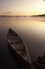 Canoa sulla riva con prealba scena di lago selvaggio nel parco Algonquin, Ontario, Canada — Foto stock