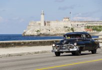Auto d'epoca americana a cavallo lungo Malecon con pittoresca vista sulla fortezza del Castello di Morro, baia dell'Avana, L'Avana, Cuba — Foto stock