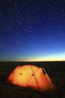 Палатка освещалась ночью с видом на долину реки Френчман, Национальный парк Грасслендс, Саскачеван, Канада — стоковое фото
