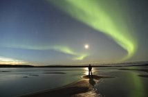 Persona in piedi lungo la riva del fiume MacKenzie con aurora boreale sopra la testa, Territori del Nord-Ovest, Canada . — Foto stock