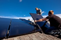 Dois instaladores de painéis solares instalam painéis solares no telhado, em Alberta, perto de Black Diamond, Alberta, Canadá. — Fotografia de Stock