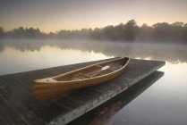 Moored wooden canoe on pier on Muskoka lake in Ontario, Canada — Stock Photo