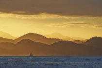 Sailboat silhouette at sunrise sailing by Inside Passage, British Columbia, Canada — Stock Photo