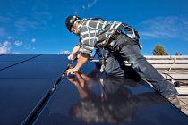 Two solar panel installers install solar panels on roof, Alberta foothills near Black Diamond, Alberta, Canada. — Stock Photo