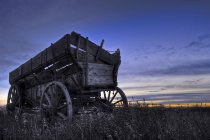 Старий дерев'яний вагона на полі на заході сонця в Альберті, Канада — стокове фото