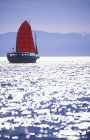 Red sailed boat on waterfront with Olympic Mountains in distance, Victoria, Vancouver Island, British Columbia, Canada. — Stock Photo